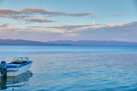 Kurbulik, Republic of Buryatia, Russia - July 11, 2022: The shore of the Holy Nose Peninsula in the Chivyrkuy Bay of Lake Baikal with boats tied up during a colorful sunset.のeditorial素材