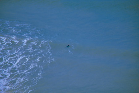 A surfer rides a wave of the sea. View from the height of a multi-storey buildingの写真素材