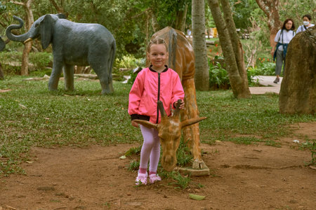 A little European girl in a pink jacket walks through the territory of the LinUng Buddhist Temple on the Seoncha Peninsula near Da Nang, Vietnamの写真素材