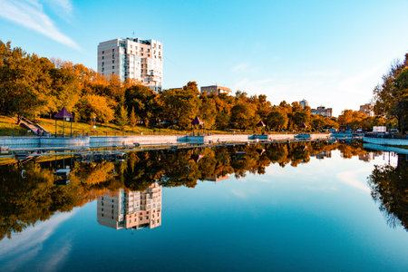 City ponds in the autumn. Trees covered with yellow and orange leaves are reflected in the water. blue sky.の写真素材