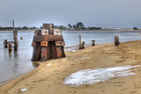 desolate winter beach with decaying pier pilings and snowの写真素材