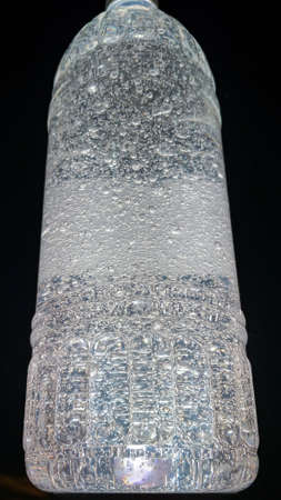 Bottle with alcohol gel, with a black background, highlighting the texture of the product presented in the form of bubblesの写真素材