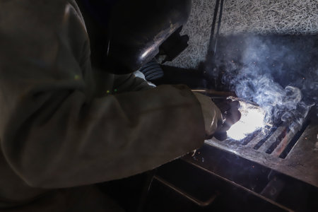 Sparks and light from work. In the image, it is possible to see the worker's hands and the professional's maskの写真素材