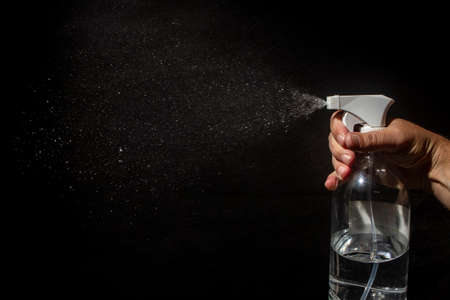 On a black background, male hand open a spray