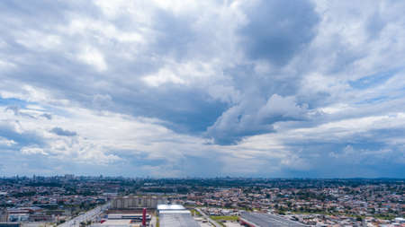 Drone image of bluish clouds, some rain formations, and the city at the bottom of the photo