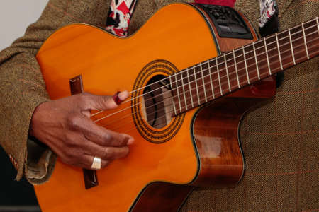 Image of a guitar player, without identifying the face, highlighting his hand, which is old, and is...