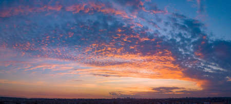 End of the day with a sky between clouds and very colorful, highlighting blue and orange. At the base of the image, and in the background, is the silhouette of the city.の写真素材