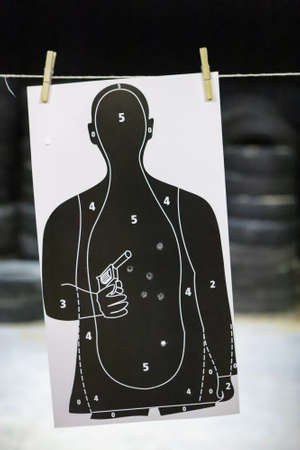 Target in white and black colors already used for shooting training, with shot holes, and tires in...
