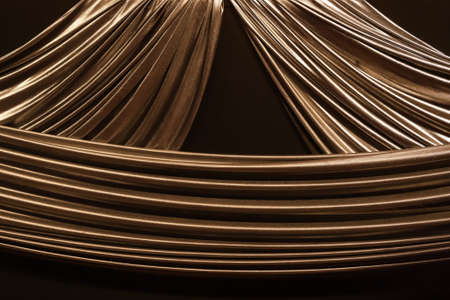 Golden fabrics that tied together form ripples contrasting with the black color