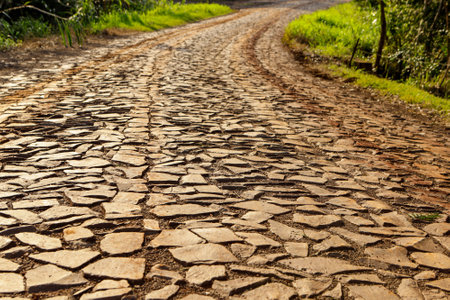 Road in a rural area made of irregular stones, with an orange hue at sunrise.の写真素材