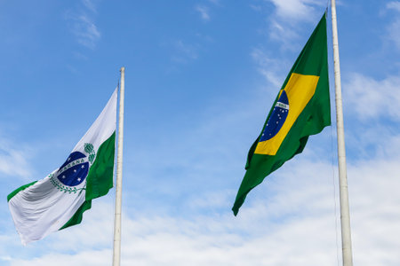 Flags of Brazil and the state of ParanÃ¡, located in the southern region of the country, on a blue sky between clouds.の写真素材