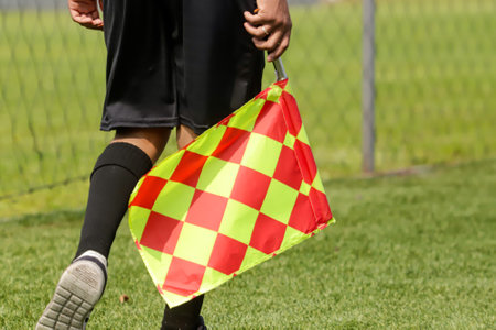 Football referee who oversees the sides of the field, known as linesmen, or assistants to the main referee. He stands out for his black attire and the checkered flag in his hand with the colors red and yellow.の写真素材