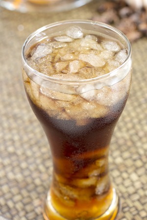 Cola in glass on woven bamboo background