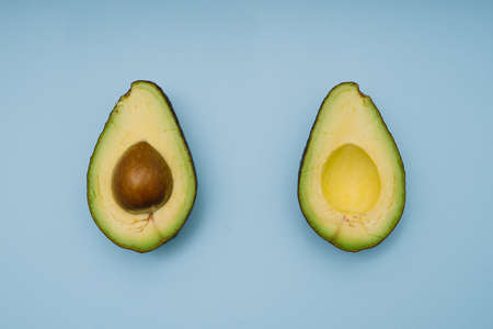 Avocado halves on orange background. Flat lay.の写真素材