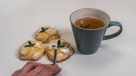Homemade cupcakes (cake) with medical marijuana and a cap of tea with marijuana leaves on white background. Cannabis joint in man handの写真素材