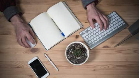 Office workplace with Hands. Business. Laptop, daily planner, glasses and phone on a wooden table. Top Viewの写真素材