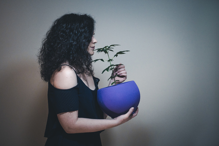 The woman with medical marijuana plant in hand. Cannabis growing indoorの写真素材