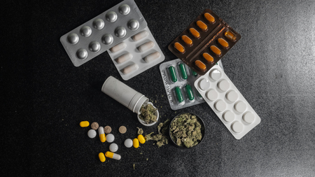Medical marijuana buds in every first aid kit. pills and cannabis lie on a black background....