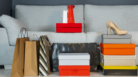 boxes with shoes and shopping bags on the background of a gray sofa