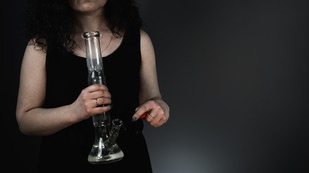 The person smoking marijuana with bong, close-up. Bong in the hand.