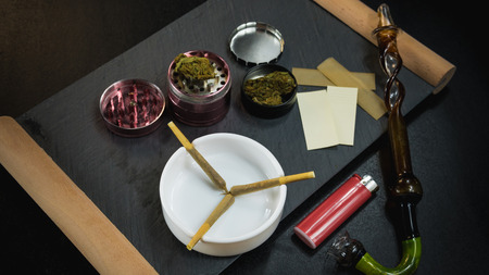 Marijuana joints lie in the ashtray. Smoking pipe, grinder, cannabis. Cannabis is herbal medicine