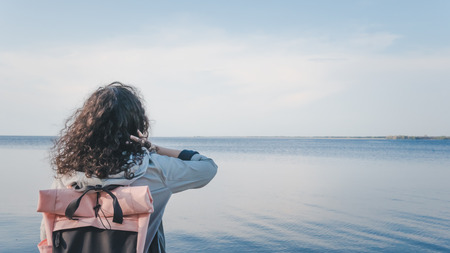 The pensive woman standing near the sea. The girl looking at the horizonの写真素材