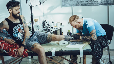 Professional tattoo artist stuffs a tattoo on a persons's body. Tattoo creation processのeditorial素材