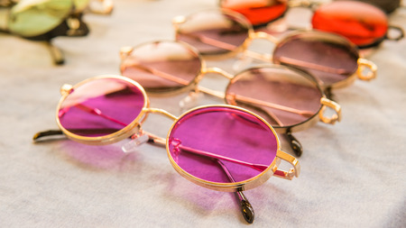 Set of colorful sunglasses for sale in a store. Different sunglasses on light coloured background. Summer eyeglasses.Fashion collectionの写真素材