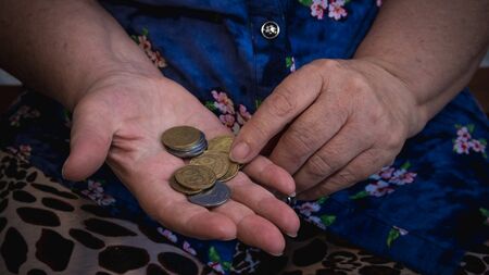 Old woman begs for alms. Closeup of money and coins in hand of poor woman. Social problems of societyの写真素材