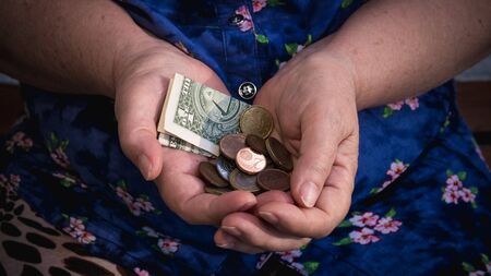 Old woman begs for alms. Closeup of money and coins in hand of poor woman. Social problems of societyの写真素材