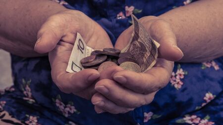 Old woman begs for alms. Closeup of money and coins in hand of poor woman. Social problems of societyの写真素材