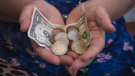 Old woman begs for alms. Closeup of money and coins in hand of poor woman. Social problems of...