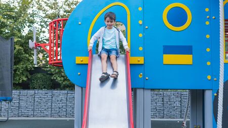 Happy smiling child on playground. Happy kids playing outdoors, clear summer day