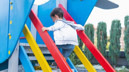 Happy smiling child on playground. Happy kids playing outdoors, clear summer day