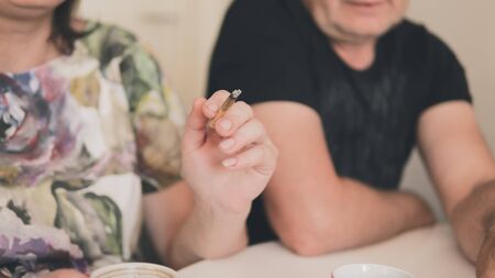 The couple of adult persons are smoking medical marijuana joint. Smoking hemp indoors. Cannabis is a...