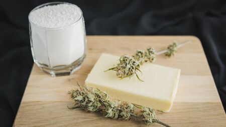 Preparing to cooking cake with cannabis butter. Concept of using marijuana in food industry. Cake with CBD cannabis and buds of marijuana on the tableの写真素材