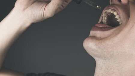 The young person using hemp oil, close-up. Cannabis oil is a concept of herbal medicine. Alternative medicine with marijuanaの写真素材