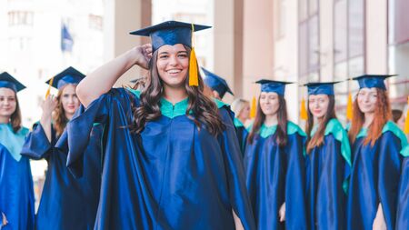 A group of young female graduates. Female graduate is smiling against the background of university graduates. Concept of education, graduation and knowledge.の写真素材