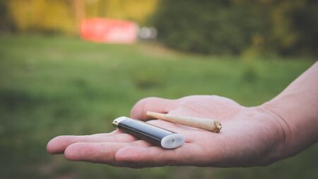 Close-up of males hands holding marijuana joint, smoking cannabis blunt outdoors. Cannabis is a concept of herbal medicineの写真素材