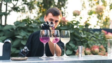 Bartender making alcoholic cocktail, summer cocktail outdoors. Colorful cocktail on top of the bar. Summer refreshment drinks. Light pink rose cocktailの写真素材