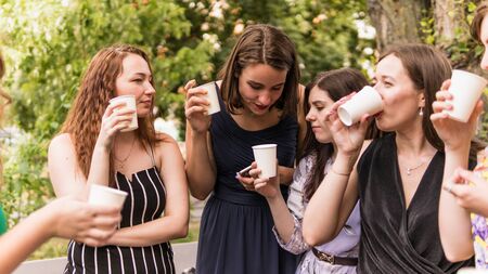 Group of girlfriends toasting with champagne in paper glass. Young people celebrating with champagne...