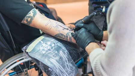 Professional tattoo artist makes a tattoo on a young manâ€™s hand, close-up. Tattoo artist...