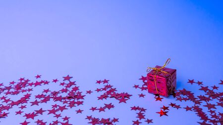 Red gift box with golden ribbon on trendy neon color background, close-up. levitation and copy space. Concept sales, discount price, Christmas and New Year presents and shopping.の写真素材