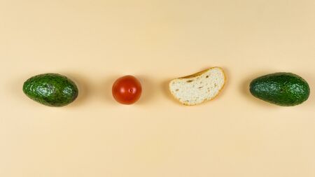 Flat lay of ripe avocado on yellow background, tomato and bread. Cooking and eating vegan sandwich....