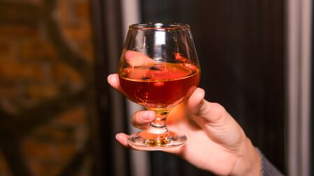 Close-up of persons hand holding glass with whiskey or bourbon. Concept of nightlifeの写真素材