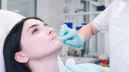 Beautician hands making  injection in  lips. The doctor cosmetologist makes lip augmentation procedure. Concept of beauty salon and plastic surgery clinic.の写真素材
