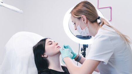 Beautician hands making  injection in  lips. The doctor cosmetologist makes lip augmentation procedure. Concept of beauty salon and plastic surgery clinic.の写真素材