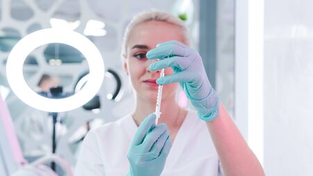 Close-up of female doctor hand with protective rubber gloves holding syringe with vaccine.  Medicine safety and health care concepts.の写真素材