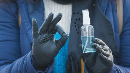 Close-up of young person holding in the hand antiseptic or anti bacteria spray. Disinfecting hands. Concept of health care during an epidemic or pandemicの写真素材