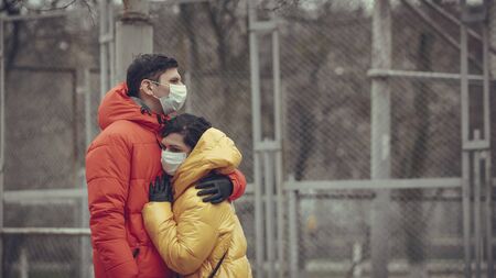 Close-up portrait of young europeans couple in protective disposable medical face mask walking outdoors. New coronavirus (COVID-19). Concept of health care during an epidemic or pandemicの写真素材